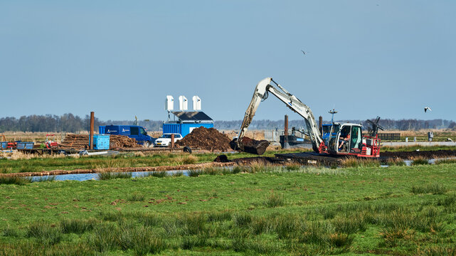 A wetland restoration project in the Wormer en Jisperveld nature reserve in the Netherlands showing an excavator dredging a ditch to promote biodiversity and ecological balance The rural landscape.