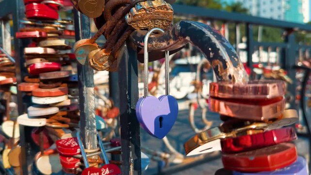 Heart shaped love lock highlighting a collection of padlocks attached to a metal railing, representing enduring love, tradition, and strong relationships