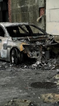 Burned out car wreck abandoned on city street. Destroyed vehicle after fire accident. Vehicle hulk as result of war conflict or arson. Urban catastrophe and property damage concept.