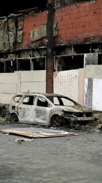 Burned out car wreck abandoned on city street. Destroyed vehicle after fire accident. Vehicle hulk as result of war conflict or arson. Urban catastrophe and property damage concept.