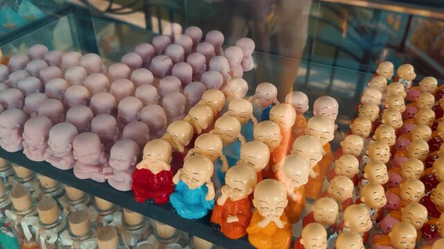 Rows of small, smiling monk figurines creating a vibrant display, portraying different expressions and meditative postures, symbolizing buddhism, peace, and mindfulness as popular souvenirs