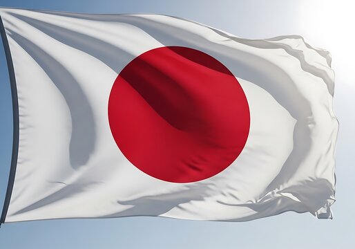 The national flag of Japan the Hinomaru waves majestically in a gentle breeze against a clear sky