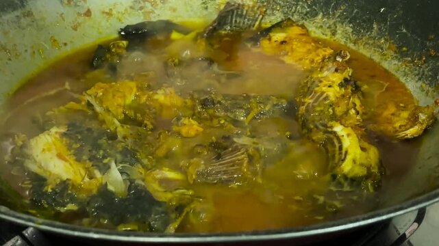 The process of cooking tilapia with a rich yellow sauce made with spices, recorded in a detailed close-up video.