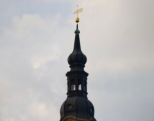 Ornate dome with weather vane. Majestic baroque spire under cloudy sky with decorative features © Vladimir