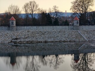 Tranquil scene showing lone figure strolling along river under winter sky with distant town © Vladimir