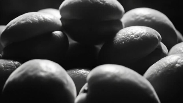 Black and white close up of a pile of apricots, fruit with textured skin, soft light and shadow