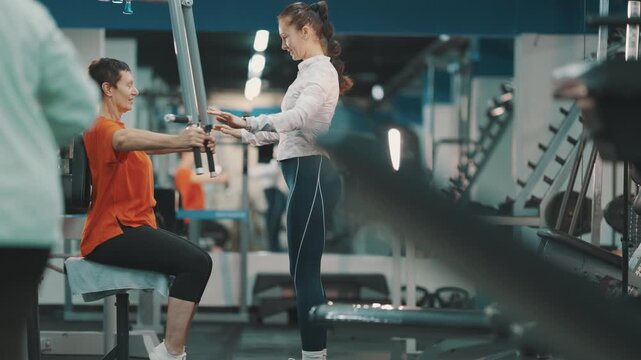 Senior woman training on chest press machine with female coach