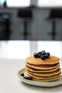 Stack of pancakes on a ceramic plate on a light surface 