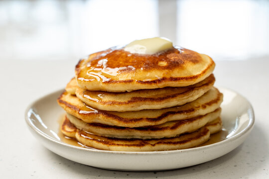 Stack of pancakes on a ceramic plate on a light surface 