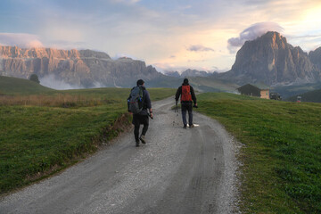 Fototapeta premium Tourists at sunset, with the Sella and Langkofel mountain ranges in the background. The Dolomites. Italy.