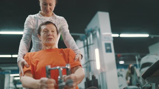 Personal trainer assisting senior woman on a rowing machine