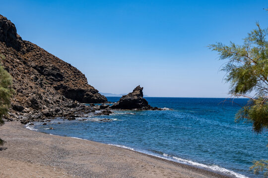 Rocky cliffs and turquoise waters at Agia Markella sandy Beach Chios Island under midday sunlight, Greece