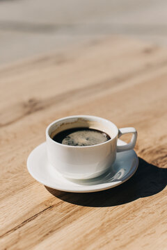 Cup of black coffee on a wooden table in a street cafe. Selective focus.