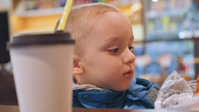 Child enjoying pastry. Toddler tastes warm bakery item. Young boy savors freshly baked treat in cozy cafe. Little child experiences delight while tasting delicious warm pastry indoors