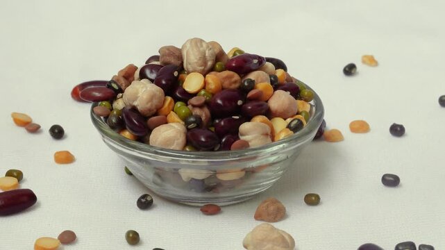 Many dried multi-colored beans closeup, an assortment of various kidney beans and peas on a white background in a glass bowl. Healthy eating, Protein intake concept.
