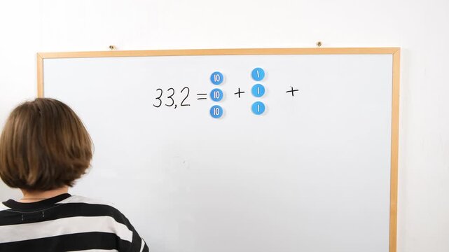Child learning arithmetic at home using magnetic numbers and place value labels on a board. Concept of homeschooling, parental support, early education, and interactive learning.