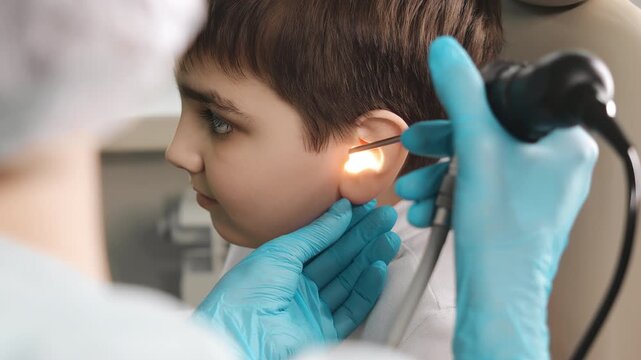 Doctor performing pediatric ear examination with endoscope on child in clinic healthcare diagnostic procedure indoors.