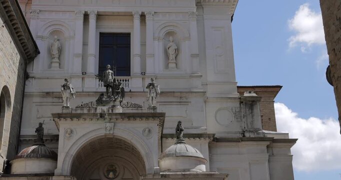 Vertical tilt up on Duomo di Bergamo facade with sculpted saints and bright white stone