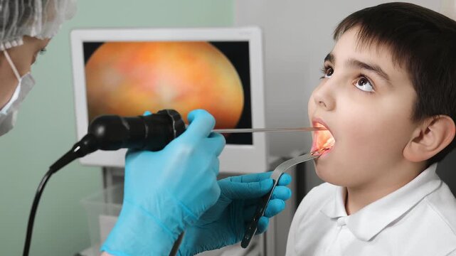 Doctor examining child throat with medical instrument during ENT checkup in clinic pediatric healthcare diagnostics indoors.