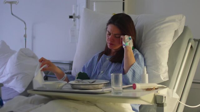 Female patient in hospital bed reaching for towel when sudden sharp pain interrupts movement, facial expression showing distress, postoperative discomfort and fragile recovery