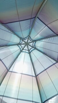 Vertical video: Shining sunlight moving down seam, causing canopy fabric shifting inside canopy hub