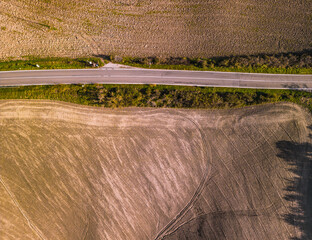 Fototapeta premium Rural road dividing agricultural fields in Tuscany, Italy.
