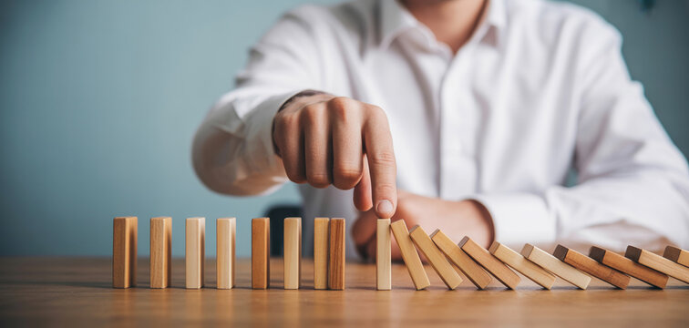 Businessman stopping domino effect, symbolizing crisis management, risk mitigation, and problem solving.