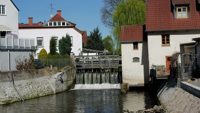 River water flowing over sluice gate with buildings