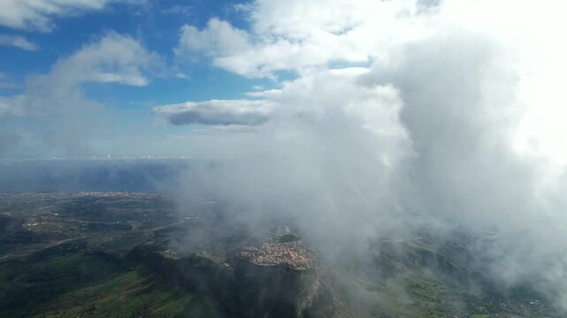 A flight and a view from the cockpit through low-hanging clouds. The fog lifts over the Aspromonte National Park in southern Italy, revealing winding mountain roads.