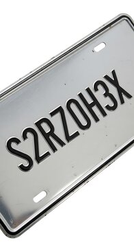 A close-up shot of a shiny, metallic rectangular plate with alphanumeric characters etched onto its surface