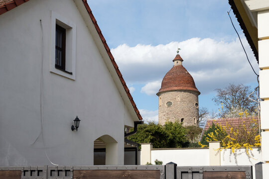 The historic Romanesque Rotunda of St. George appearing behind traditional white houses and blooming yellow bushes in Skalica, Slovakia