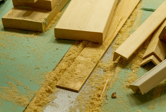 The image shows a woodworking workshop scene with raw lumber pieces scattered on a workbench covered in sawdust, showcasing the process of constructing a mortise and tenon joint. Craft