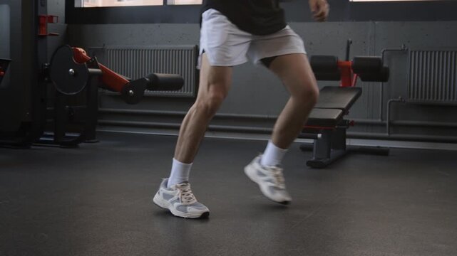 Well-built young man boxing in air, punching imaginary opponent in modern fully equipped gym