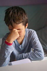 Obraz premium Tired but Focused Child Studying at Home