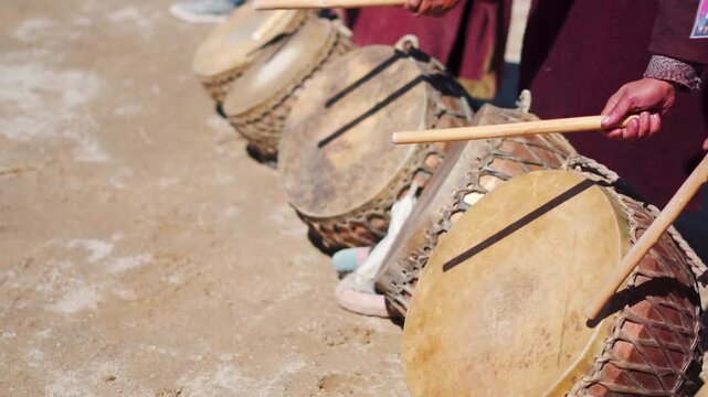 Closeup shot of hands of people playing old drums during a traditional festival at religious ceremony in Padum, Zanskar Valley at remote Ladakh, India. Traditional Cultural festival in the Himalayas.