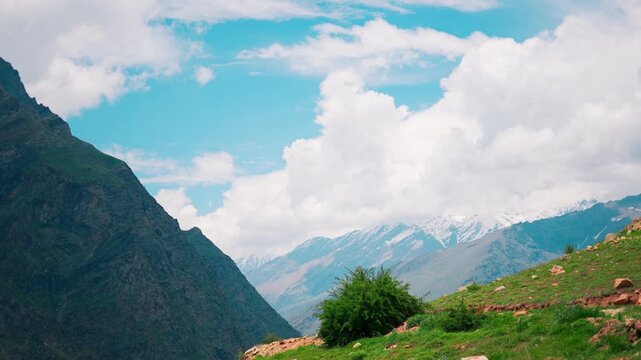 4K Landscape shot of scenic snowy Himalayas with clouds above them during the summer season as seen from Marbal Village in Lahaul and Spiti district, Himachal Pradesh, India. Natural background.