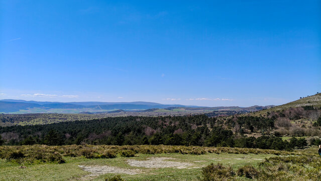 Majestuosa vista de un ca&ntilde;&oacute;n rocoso con acantilados escarpados bajo un cielo azul surcado por estelas de aviones. El paisaje monta&ntilde;oso destaca por su relieve geol&oacute;gico y vegetaci&oacute;n de matorral.