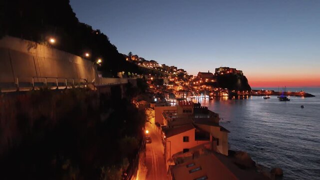 Night aerial view of Chianalea Scilla with glowing village lights and coastline