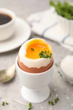 Tasty breakfast with soft boiled egg, microgreens, salt and coffee on grey table, closeup