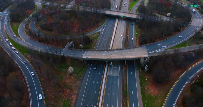 Multi-lane highways with trestles above them. Rising over the motorway with quickly moving cars. Aerial view.