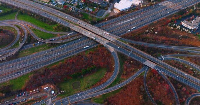 Multiple highways with numerous cars. Colorful trees are around the motorways. Aerial view.