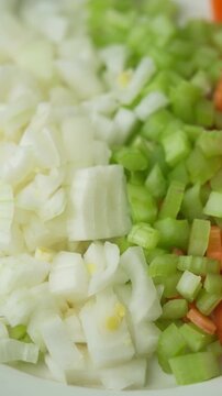 Diced Italian soffritto ingredients onion celery and carrot rotating close up