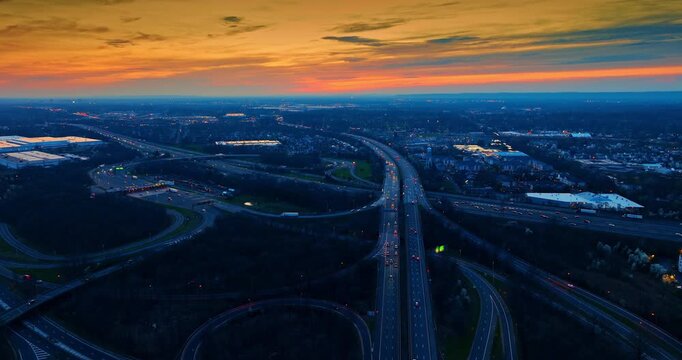 Panorama of the city crossed by the multiple modern motorways. Stunning orange sky at sunset in the backdrop. Aerial view.