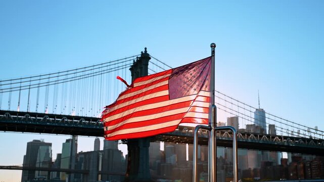 Flapping American flag against the Manhattan Bridge. Downtown skyscraper skyline in the backdrop.