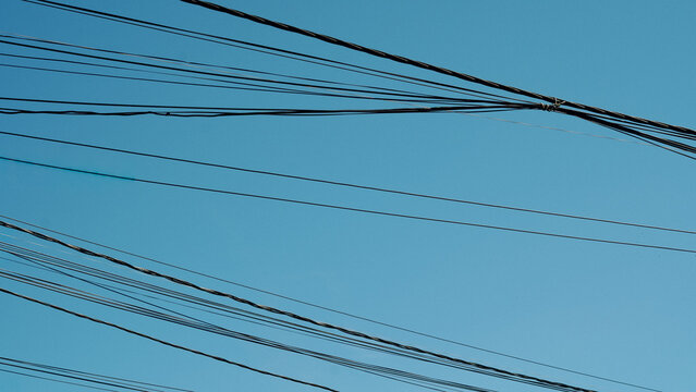 Power lines against clear blue sky in urban environment
