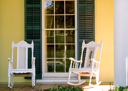 Two White Rocking Chairs on Porch with Window and Shutters Southern Lifestyle Scene