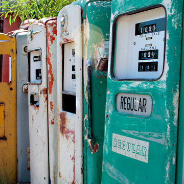 Row of weathered vintage gas pumps in faded pastel colors