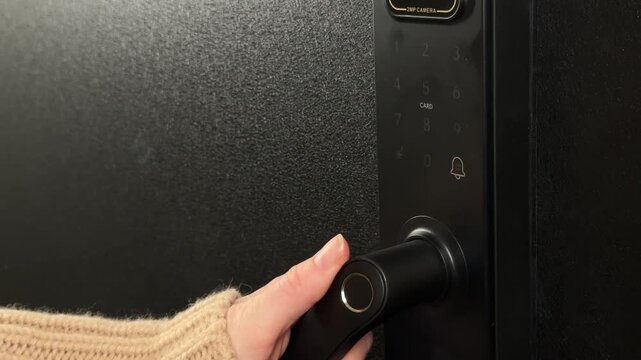A woman opens a modern smart door lock with a digital keypad using a code.