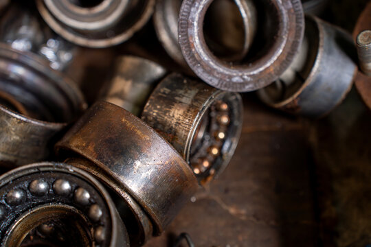Close view of used ball bearings and metal rings with grease marks, showing worn mechanical parts for repair and maintenance work.