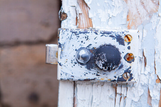 Rusty hinge on a white wooden door. Shallow depth of field.